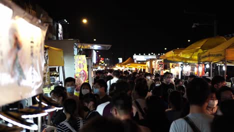 busy night market with crowds of people eating street food