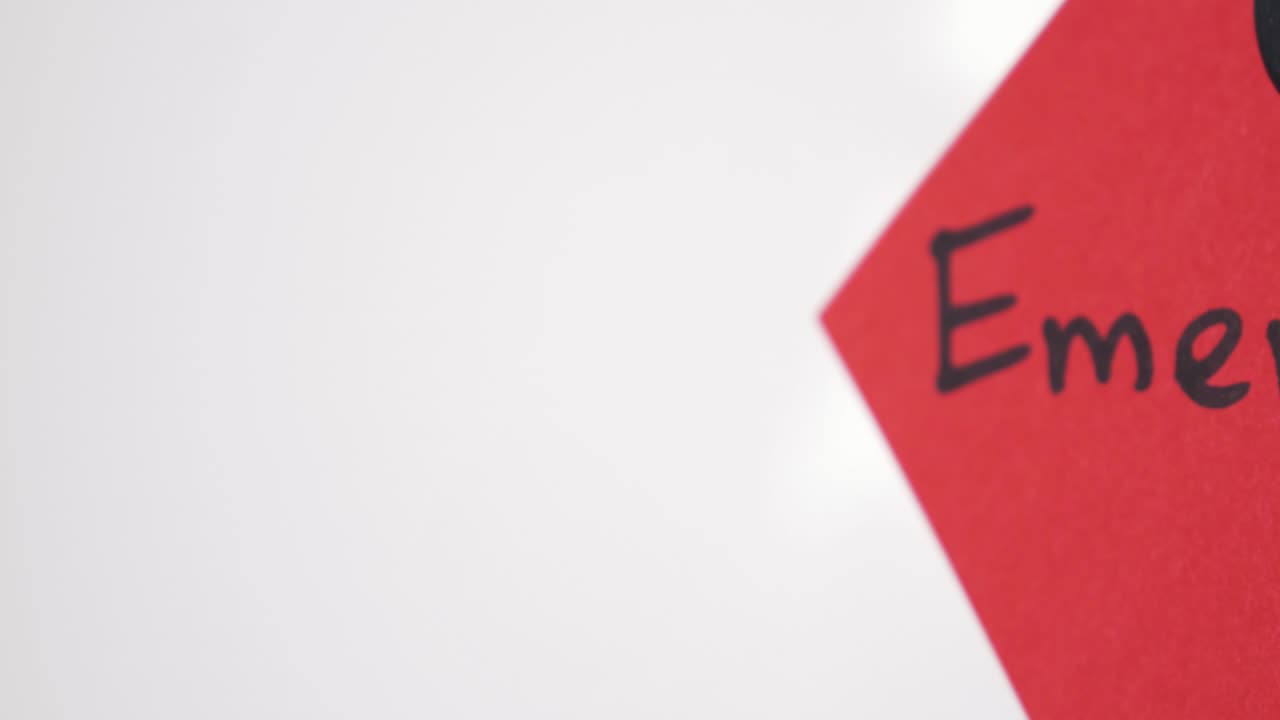 Pan reveal of Emergency text on red note held by magnet on whiteboard with selective focus