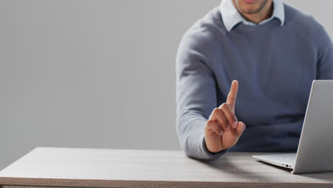 Midsection-of-biracial-businessman-using-laptop-and-holographic-display,-with-copy-space