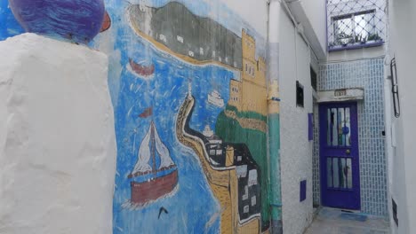 Pintura-En-Una-Pared-Blanca-En-Un-Pequeño-Callejón-En-La-Medina-De-Tánger,-Tiro-Inclinado-Hacia-Abajo