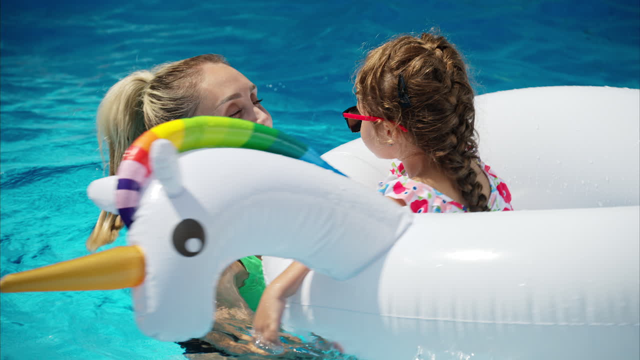 Mother with father and daughter smiling and resting and swimming in a pool in summer, white pool balloon