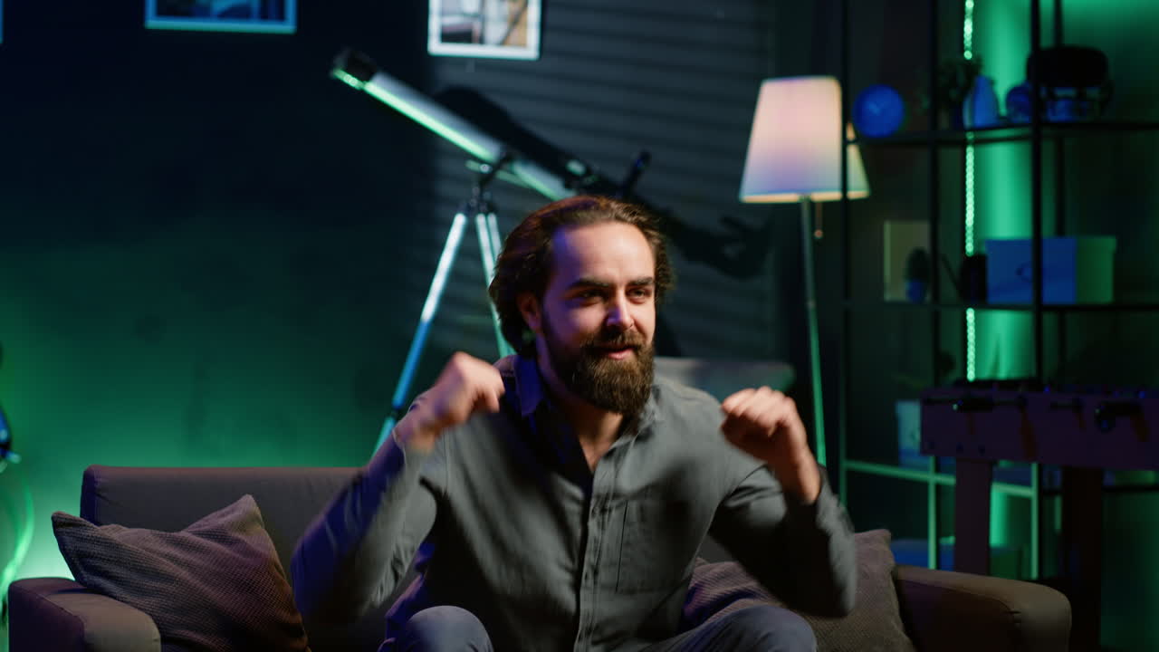 집에서 스포츠 방송을 시청하는 스타틱한 남자, 광란스러운 손짓을 하고