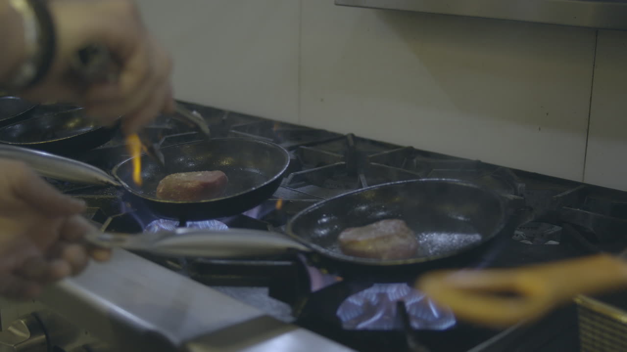 숙련된 셰프는 울부 ⁇ 는 그릴 앞에 서서,  ⁇   ⁇ 는 스테이크를 숙련적으로 조리합니다. 불에서 흡연이  ⁇ 아져 나오며, 고기를 맛있는 연기 맛으로 가득 채우고 있습니다.