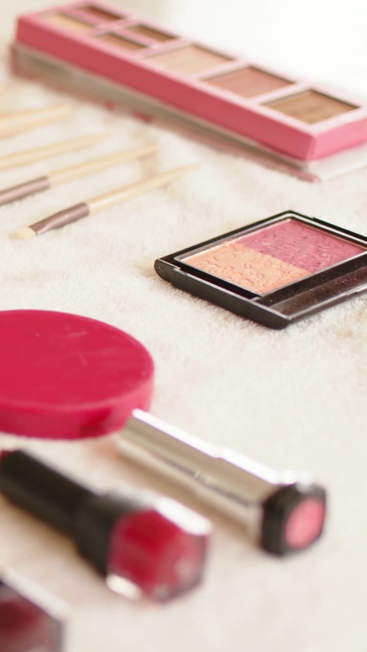 Vertical video: Panning camera revealing makeup on vanity cloth, highlighting lipsticks and palette