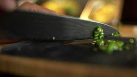 primo piano estremo delle mani femminili che tagliano a cubetti un fagiolo verde