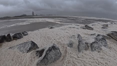 currumbin beach with sea foam during cyclone alfred in queensland, australia - wide shot