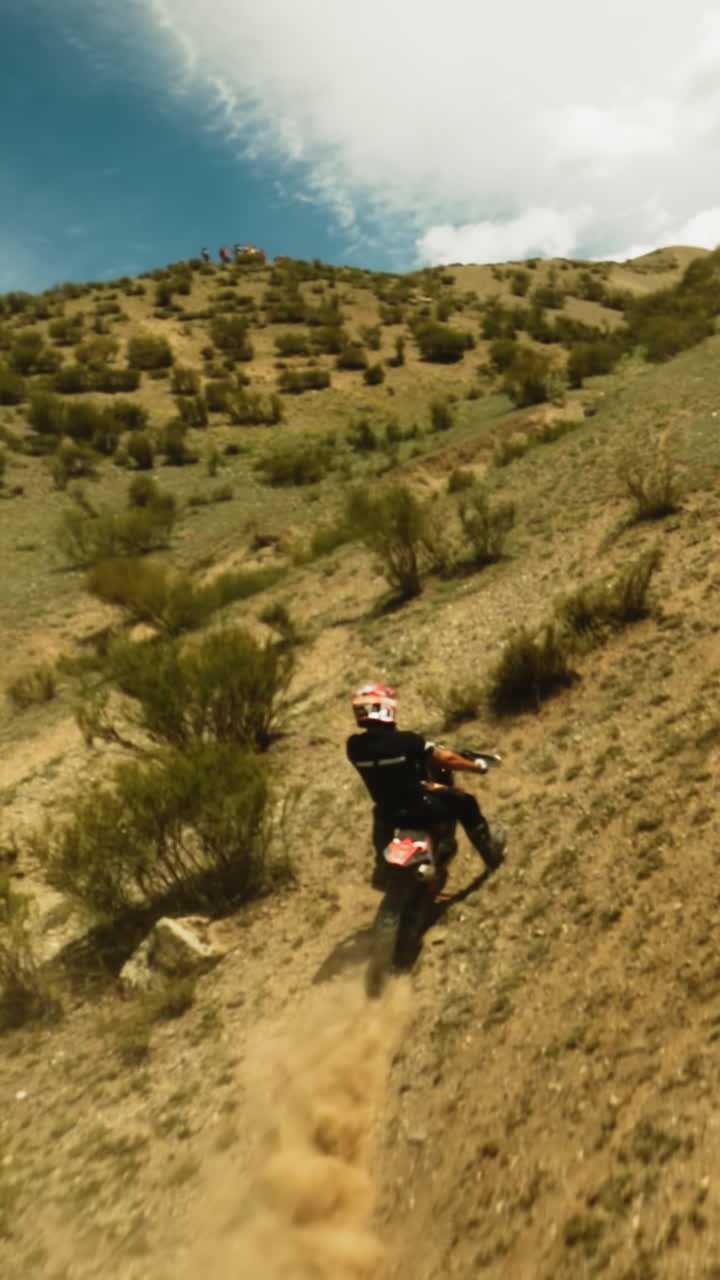 un deportista monta una motocicleta rápida en un valle polvoriento con un avión no tripulado. un motociclista en un vehículo poderoso compite en carreras fuera de carretera en las tierras altas de verano. ocio extremo