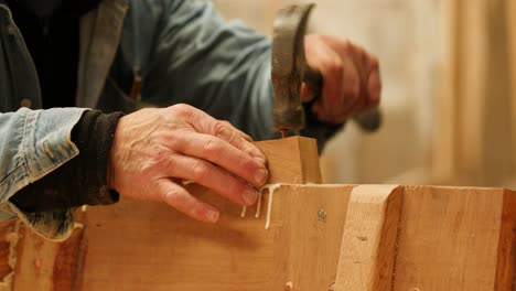 Traditional boatbuilding, carpenter hammering nails into a wooden structure