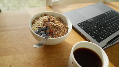 espacio de trabajo de oficina en casa de madera soleada con un tazón de desayuno nutritivo y café