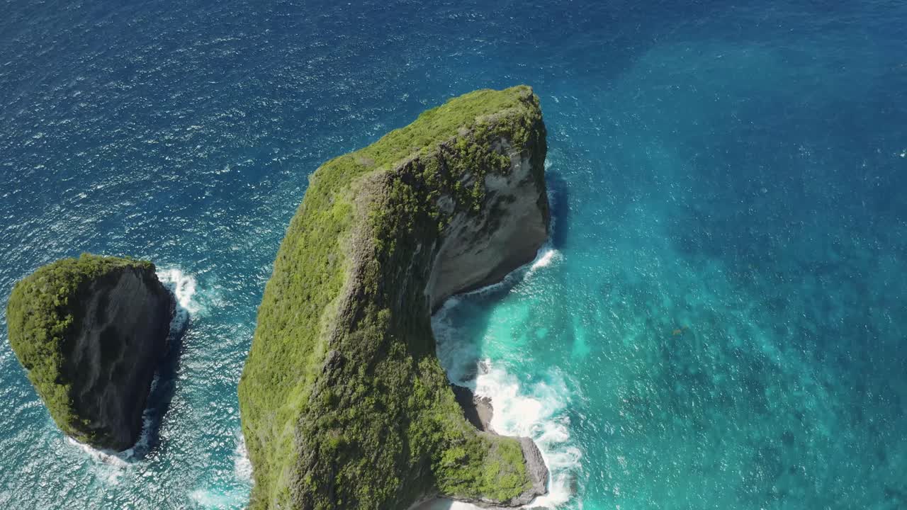 fotografía aérea de la costa de nusa penida en bali, moviéndose hacia atrás para revelar acantilados, aguas turquesas y olas del océano chocando contra la prístina playa de arena, creando una vista panorámica impresionante