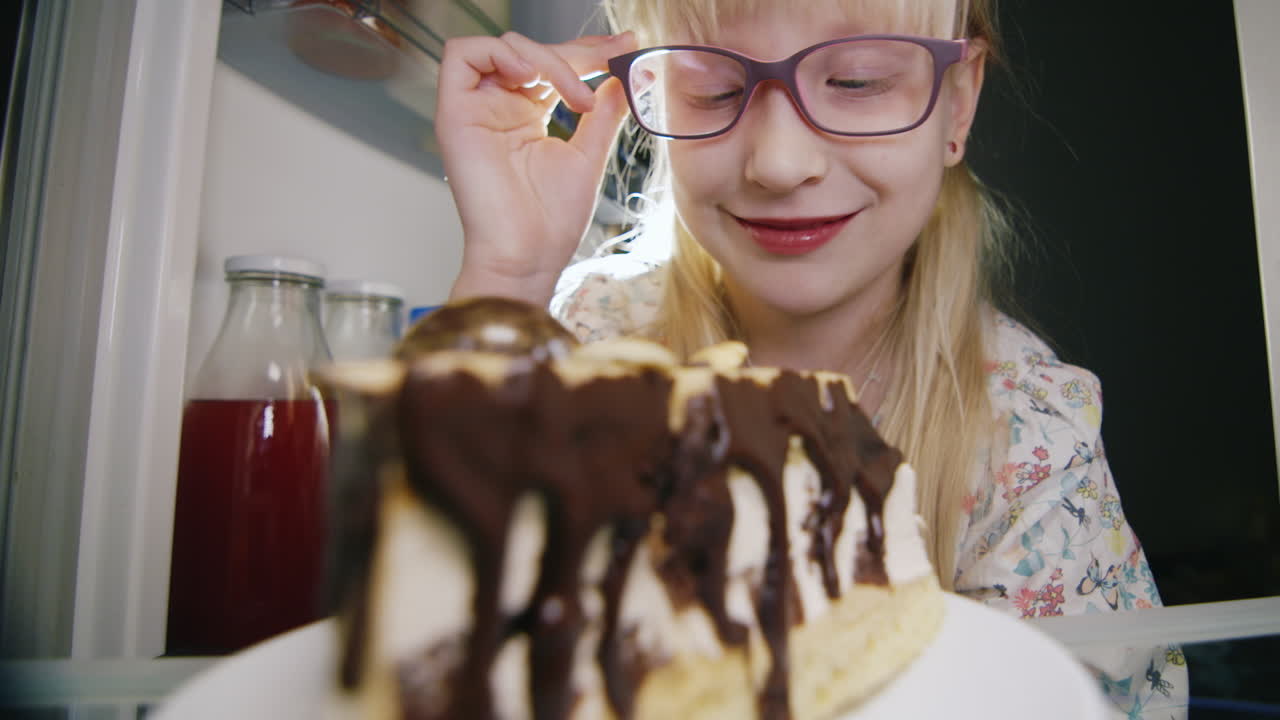 una niña pequeña prueba en secreto el pastel en la nevera 3