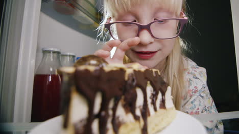 una niña pequeña prueba en secreto el pastel en la nevera 3