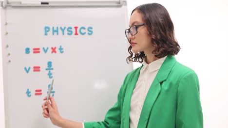 woman explaining physics formulas on a whiteboard