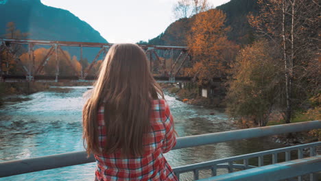 Photographer-woman-takes-Polaroid-photo-of-valley-from-bridge-among-fall-colors