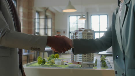 business handshake over architectural model of property development