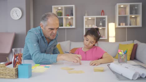 una niña estudiando con su abuelo.
