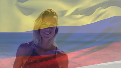 animation of colombian flag over smiling caucasian woman standing against sea at beach