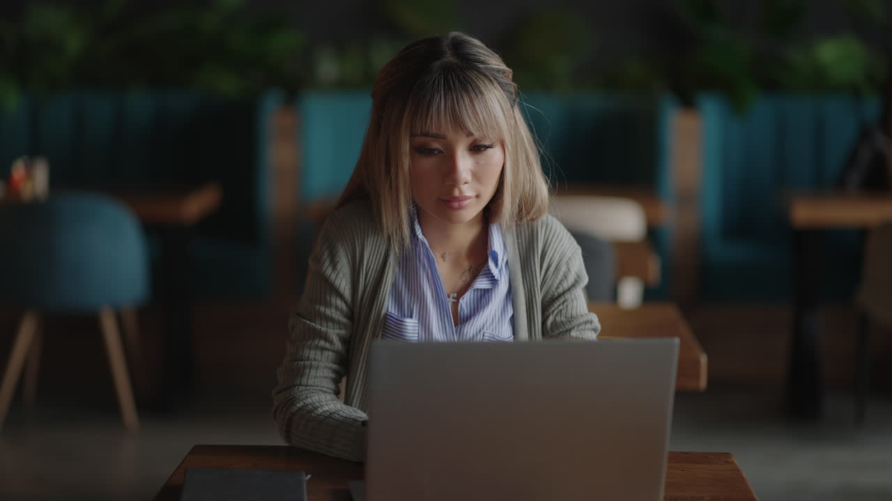 An Asian woman sits brooding and looks at a laptop screen. Brainstorm and anxious on his face. Brooding Asian woman