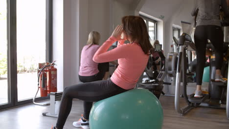 Mujer-Haciendo-Abdominales-Sobre-Una-Pelota-De-Fitness-En-Un-Gimnasio,-Vista-Lateral