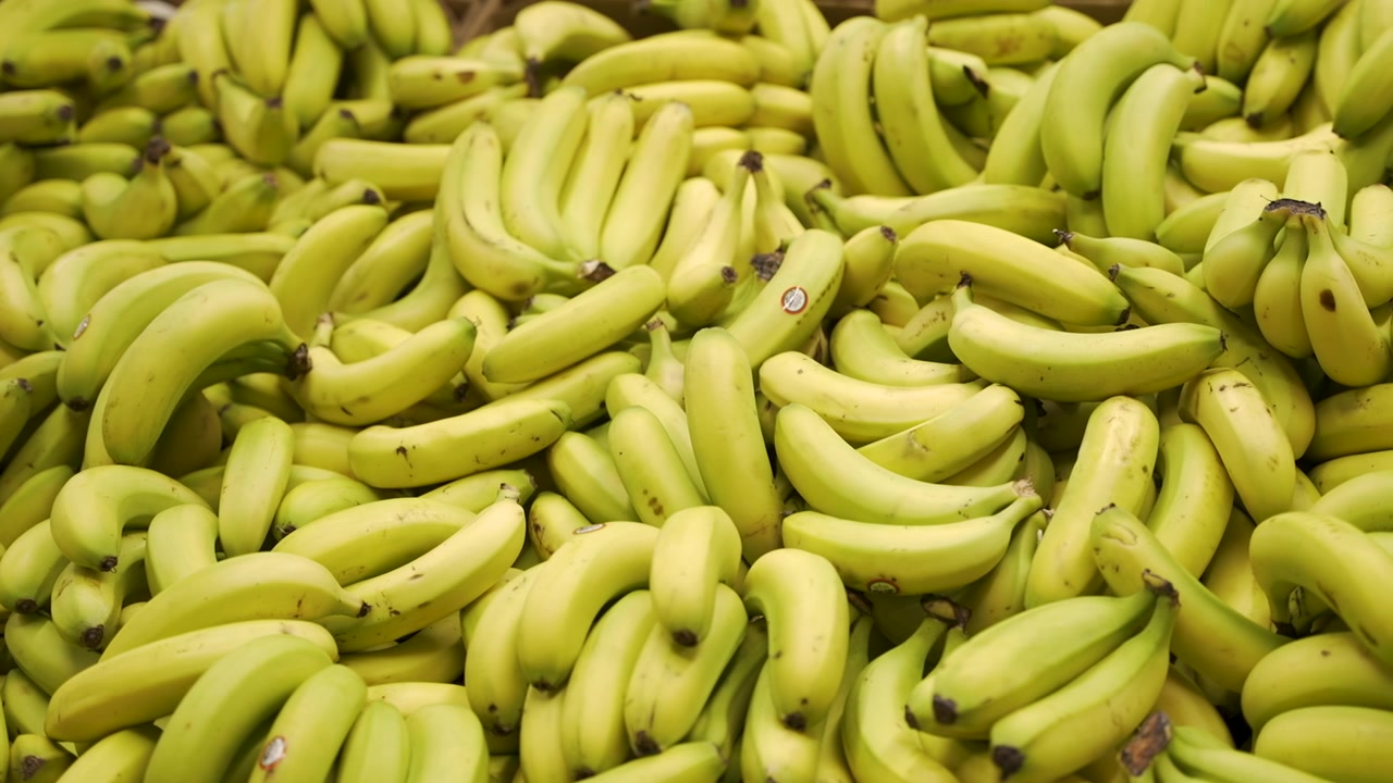 Suuri kasa kypsiä keltaisia banaaneja täyttää supermarketin hedelmälaatikon, korostaen runsautta ja terveellistä hedelmävalintaa.