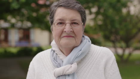 portrait of elegant elderly woman looking serious confident at camera wearing scarf in garden background