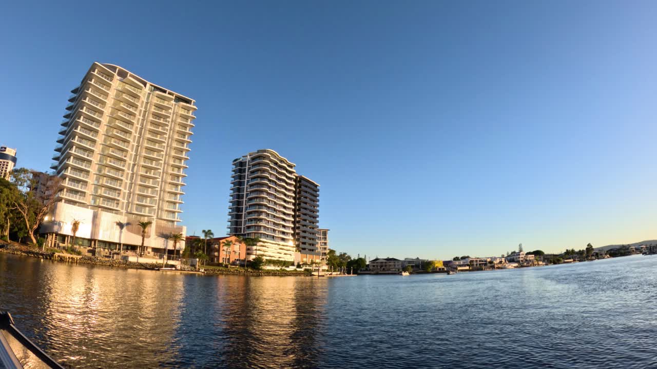 해가 지는 동안 물  에 있는 고층 건물 들