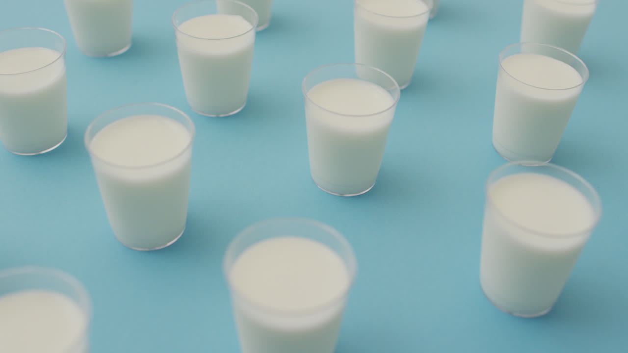 video de una fila de vasos de leche sobre un fondo azul