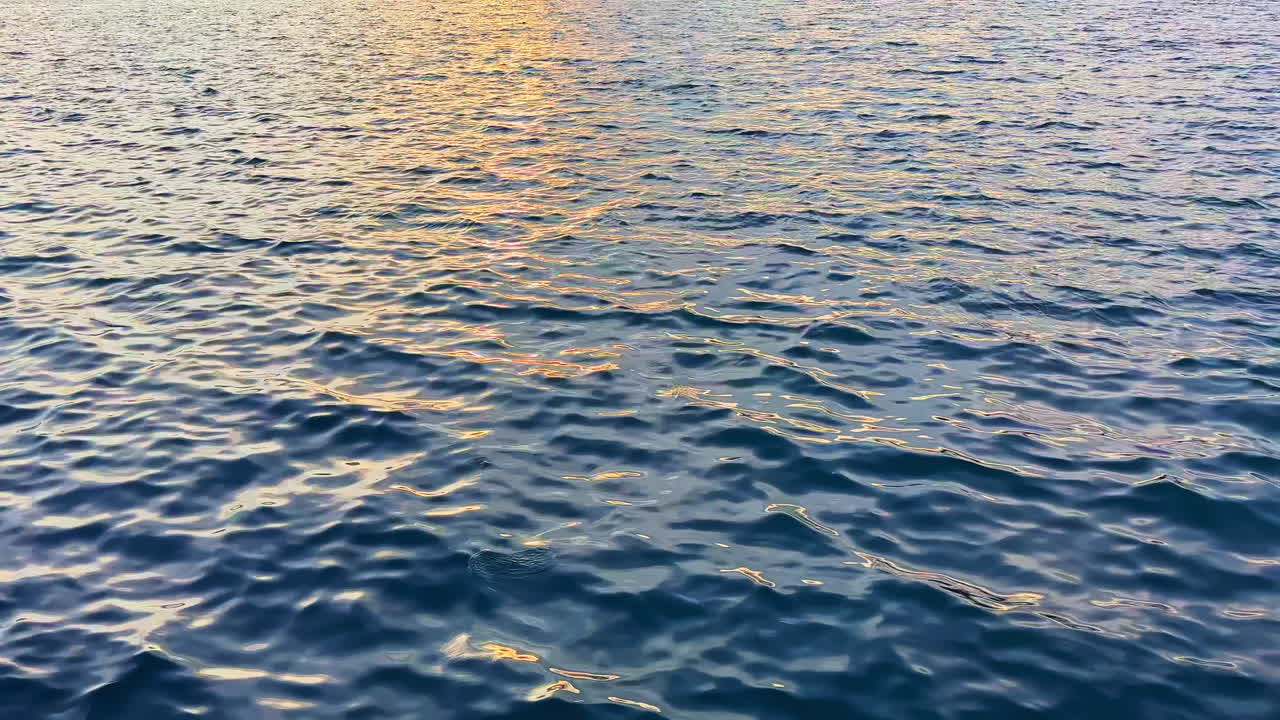 Water surface reflects light with gentle movement during sunset over the ocean