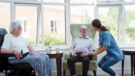 male and female residents sitting in chair and talking with nurse in retirement home