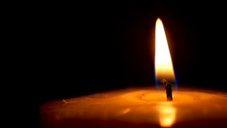 Burning-flame-of-candle-in-dark-room-with-black-background