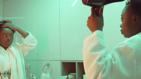 mujer afroamericana secando el cabello en el baño