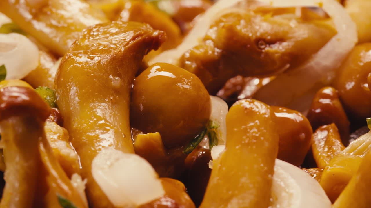 Close-up of fermented yellow honeydew mushrooms with onion on plate. Preservation of vegetables in glass jars. Fermentation preserved mushroom with spices rotating macro.