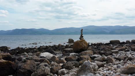 Ausgewogene-Spiritualität-Meditationskiesel,-Die-Auf-Einer-Fremden-Felsigen-Gebirgskette-Am-Strand-Aufgehäuft-Sind,-Umkreisen-Rechts