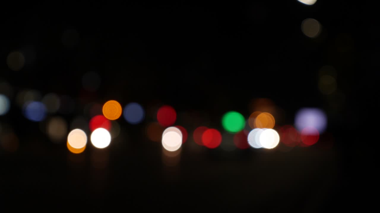 hermoso bokeh brillante en el fondo oscuro borroso por la noche. el redondo bokeh colorido brilla de las luces de los coches en la calle de la ciudad. fuera de foco con borroso. luces de la ciudad sin enfoque. bokeh de tráfico. concepto abstracto