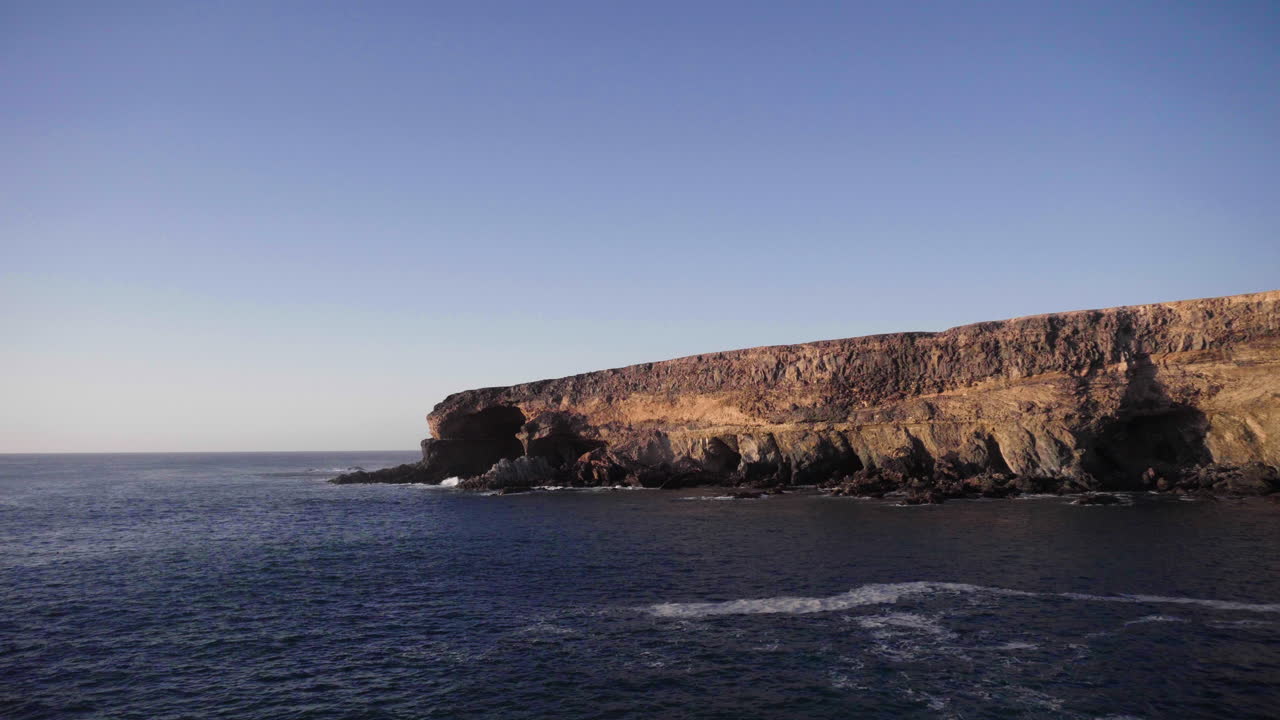 Wide view over large rock formation on the coast of the Canary Islands, Fuerteventura, with calm ocean