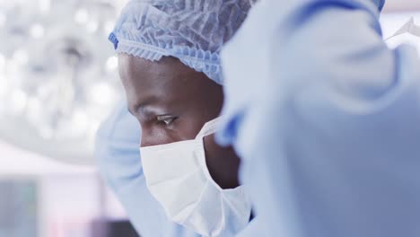 video of african american male surgeon tying face mask in operating theatre, copy space