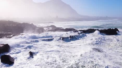 olas incesantes golpeando la costa rocosa con niebla matutina al amanecer