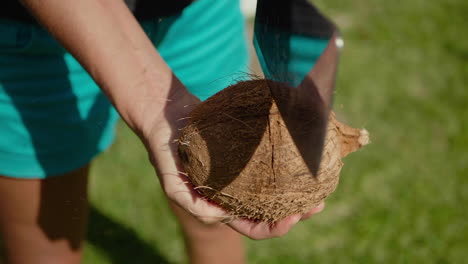 close up of woman holding coconut, chopping in half with cleaver