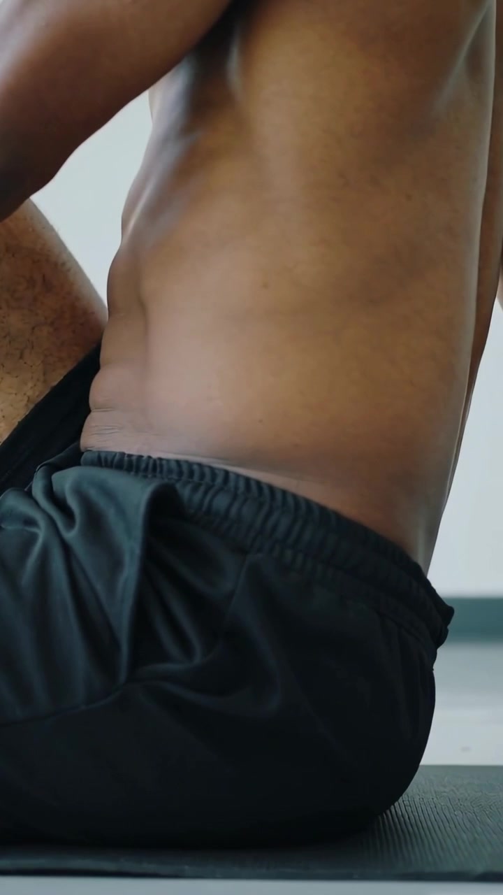 Video verticale: Uomo a torso nudo in pantaloncini neri che porta il ginocchio al petto su un tappetino, per migliorare la mobilità.