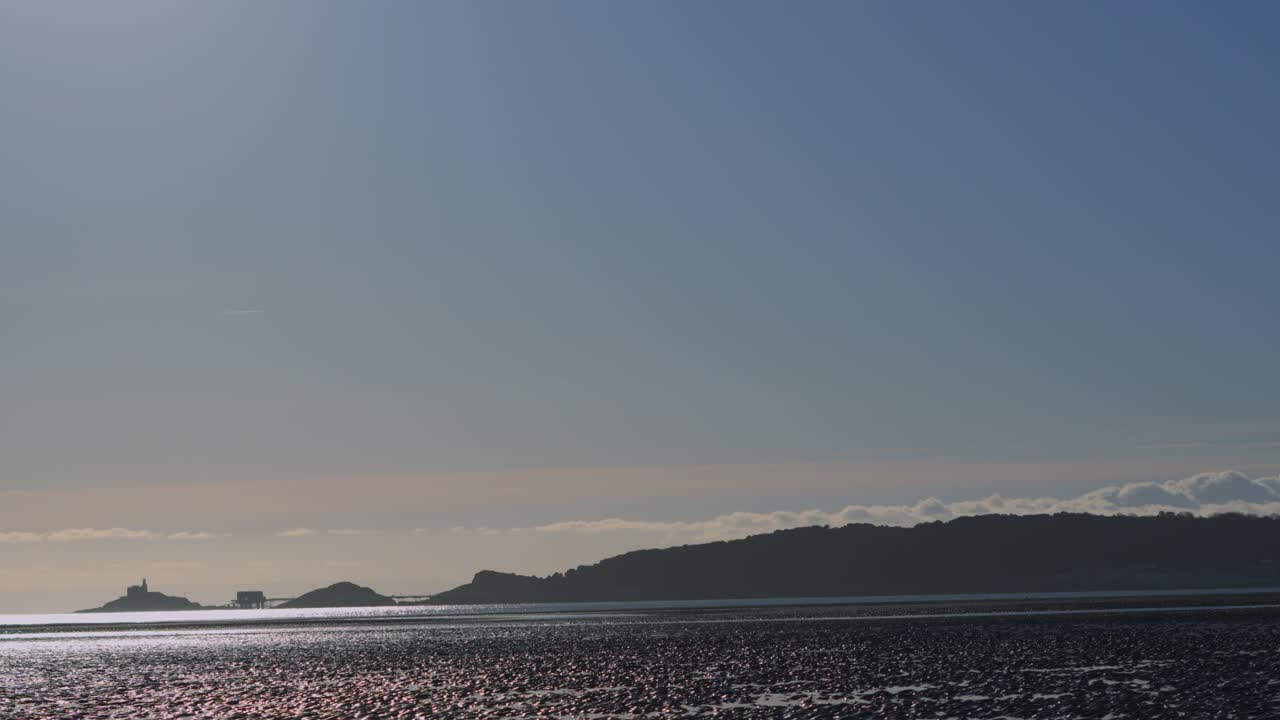 Pan Across Swansea Bay with Mumbles on Horizon Across Beach at Low Tide with Lighthouse on Small Island. Natural Footage in Wales UK.
