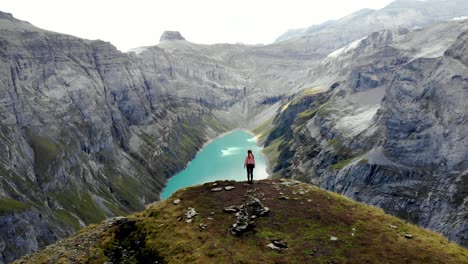 un paso elevado sobre un excursionista disfrutando de la vista sobre el lago limernsee en glarus, suiza, cuyo agua color turquesa está rodeada por altos picos y acantilados de los alpes suizos