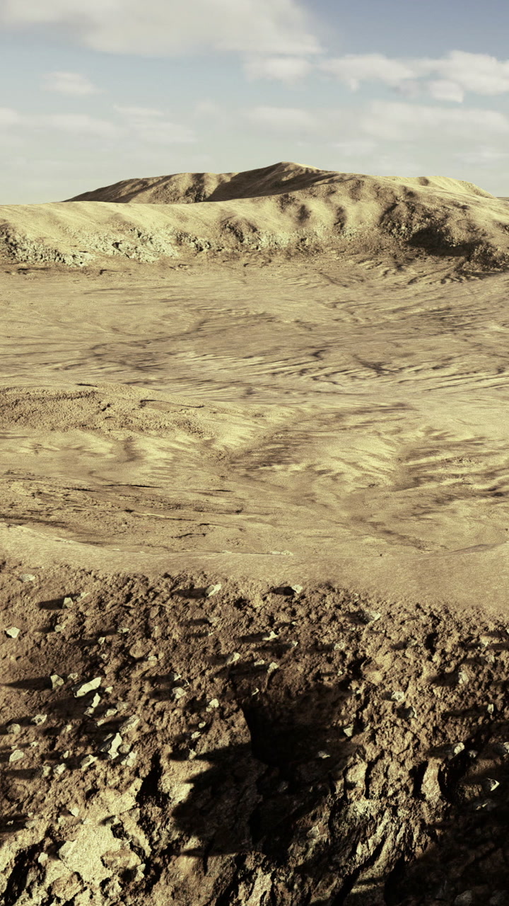 Paesaggio desertico con terreno roccioso e colline distanti sotto un cielo blu.