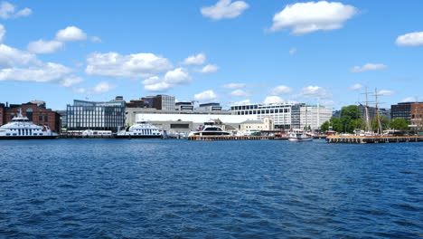 pan right shot of oslo coastline in sunny day, marina with moored and sailing boats