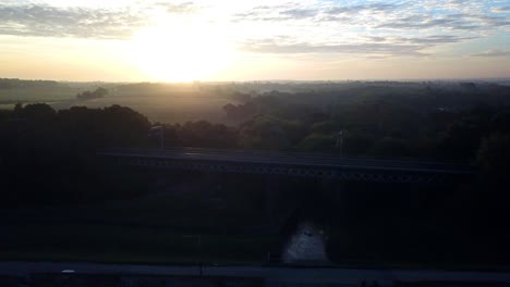 Horizontal-Absteigende-Luftaufnahme-über-Den-Sonnenuntergangshorizont-Zur-Frostigen,-Dunstigen-Eisenbahnbrücke