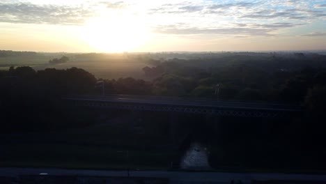 horizontal descending aerial across sunset horizon to frosty hazy rail bridge