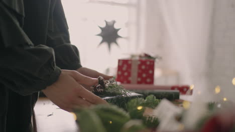 final packaging of the christmas gift on a wooden table with wrapping paper and garlands