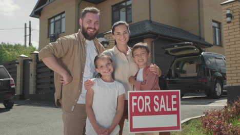 happy family posing before house for sale