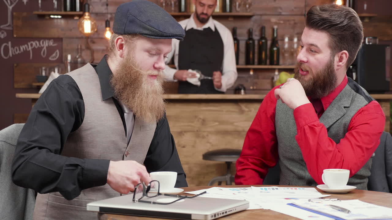 Businessmen discussing graphs over coffee in a bar