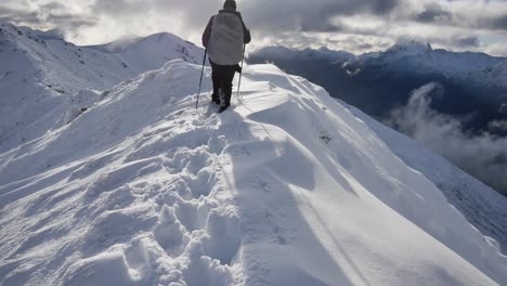 Hiker-walks-on-snowy-mountains-on-thick-snow-with-mountaineering-equipment-on-the-kepler-track,-Fiordlands