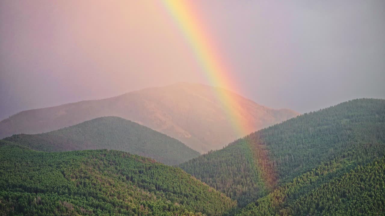 hermoso arco iris que se forma a partir de la tormenta de sol y lluvia en las colinas de las montañas
